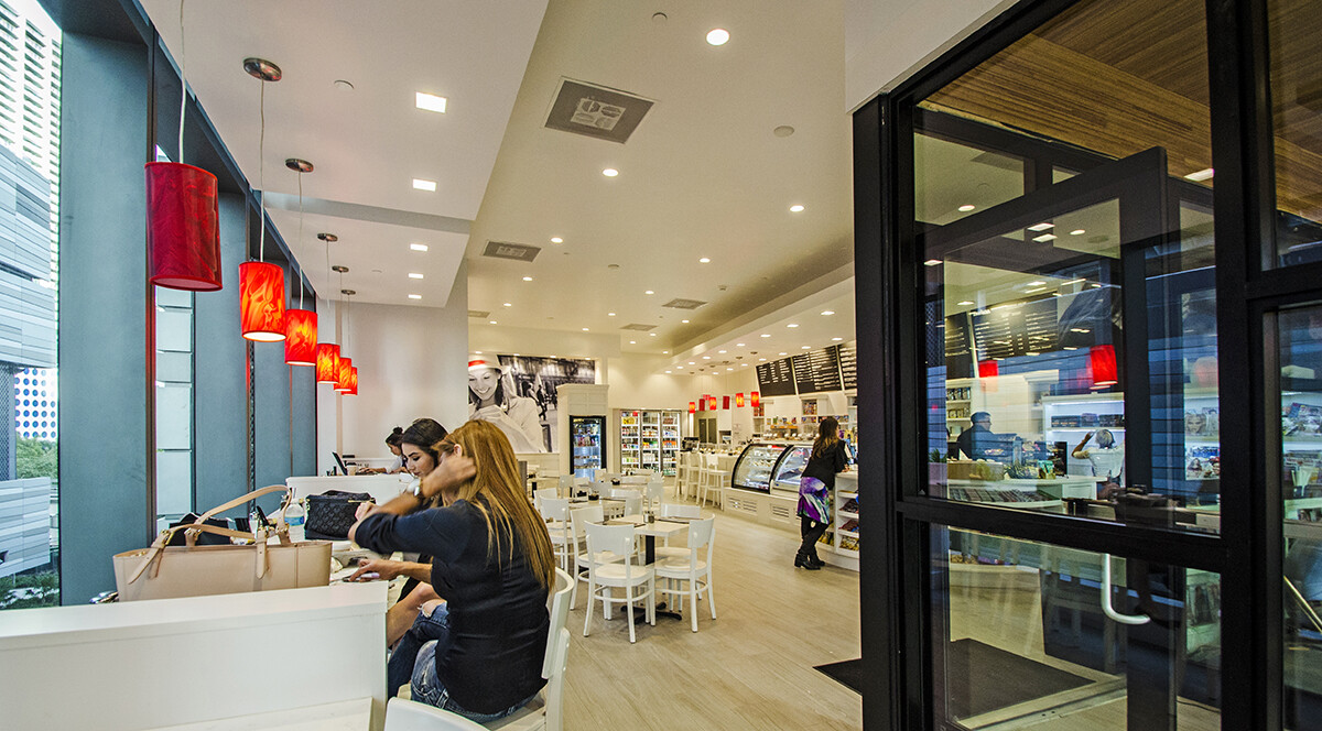 Glass entrance door and seating area inside a custom millwork Brickell coffee shop in Miami