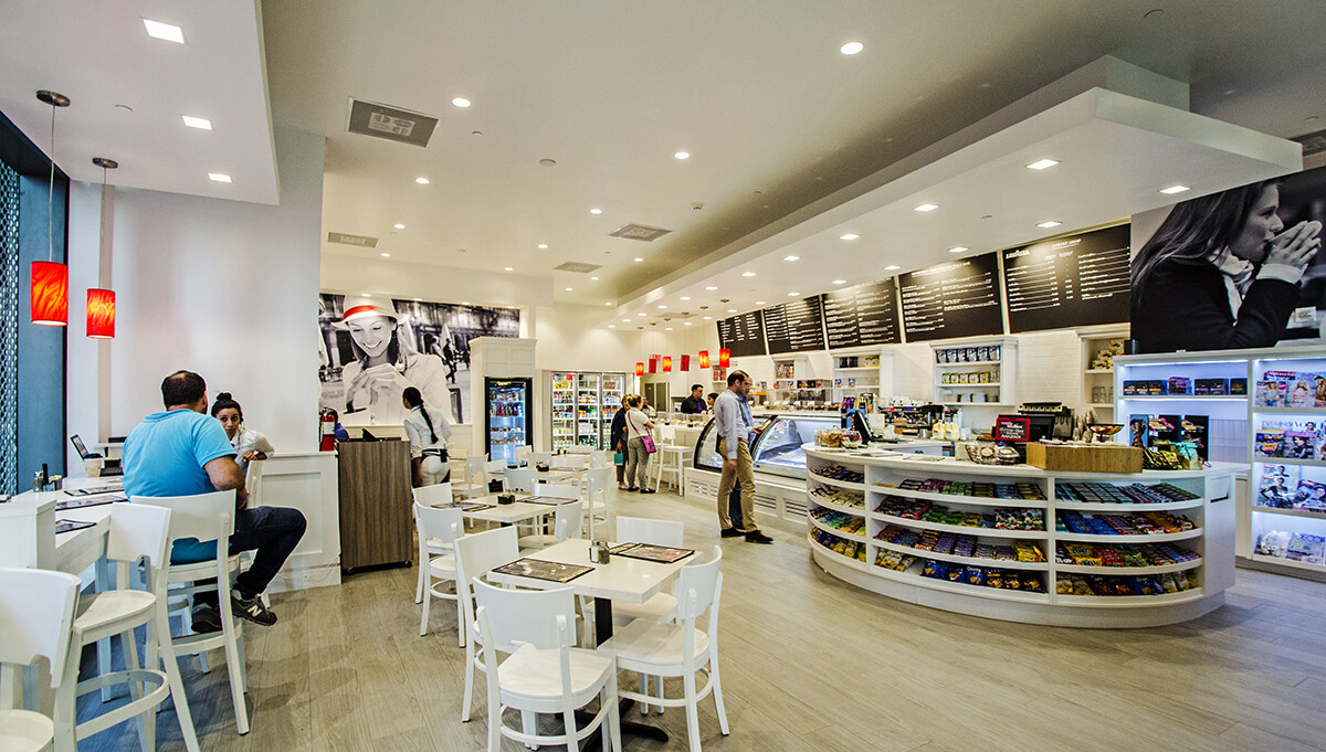 Seating area with red pendant lights and white custom millwork in a Brickell coffee shop, Miami