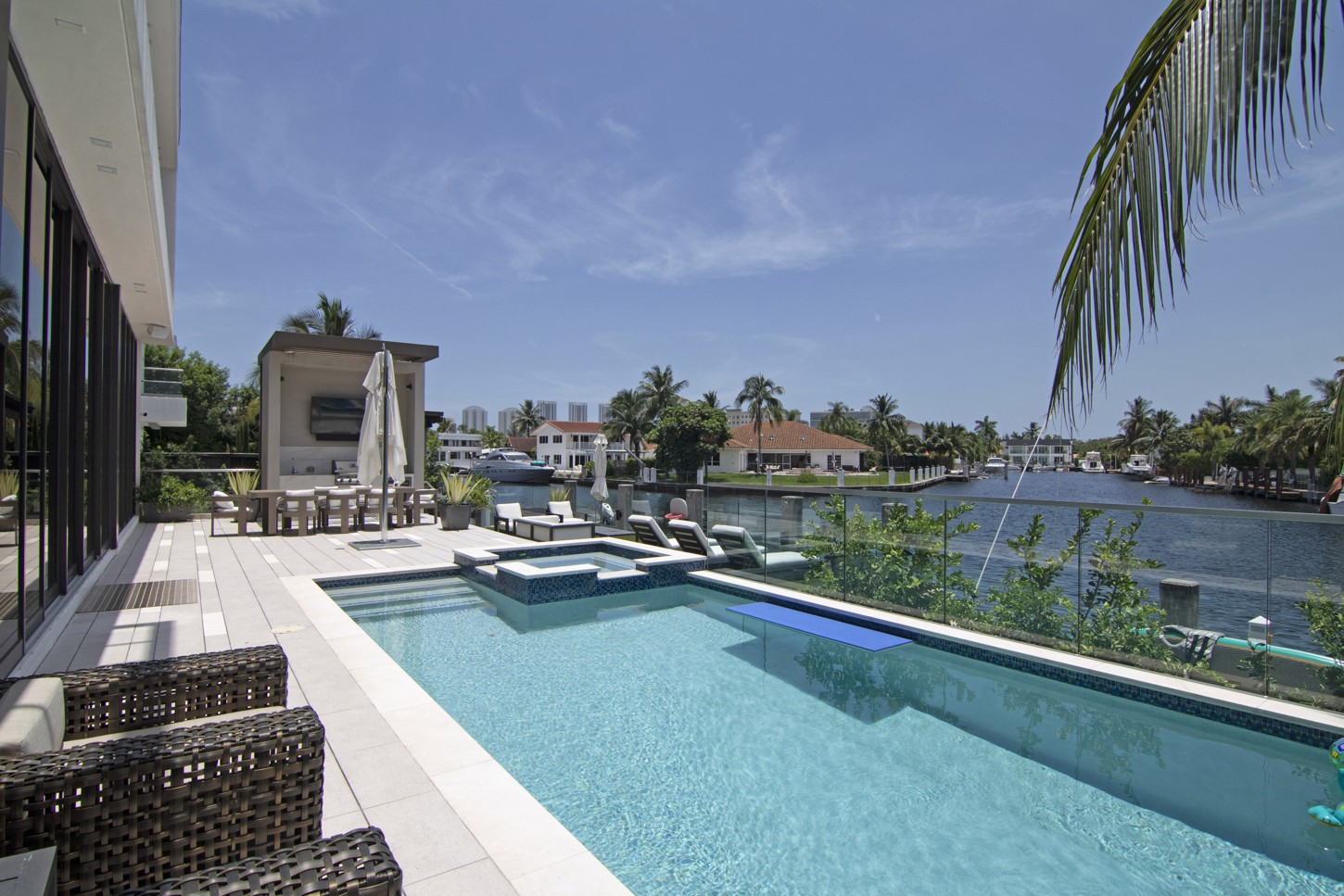 Backyard pool deck with custom outdoor furniture and waterfront view in North Miami