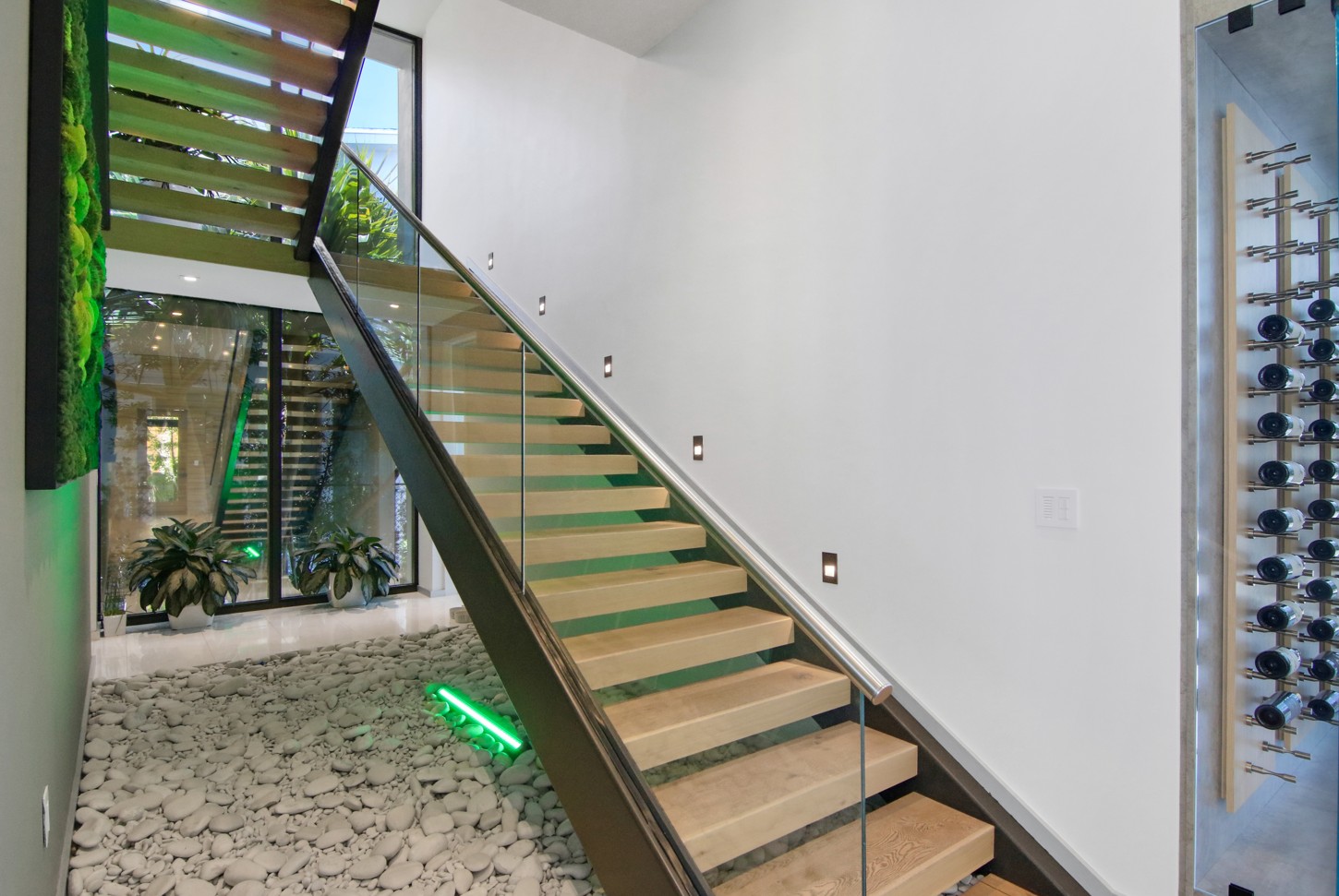 Floating staircase with glass railing and a moss wall with LED lighting in North Miami
