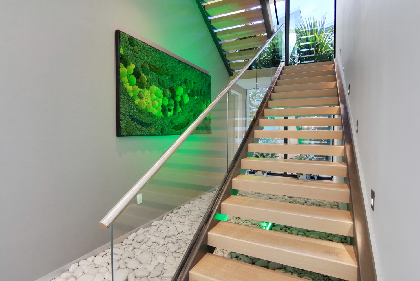 Floating staircase with wood treads, glass railing and moss wall in North Miami