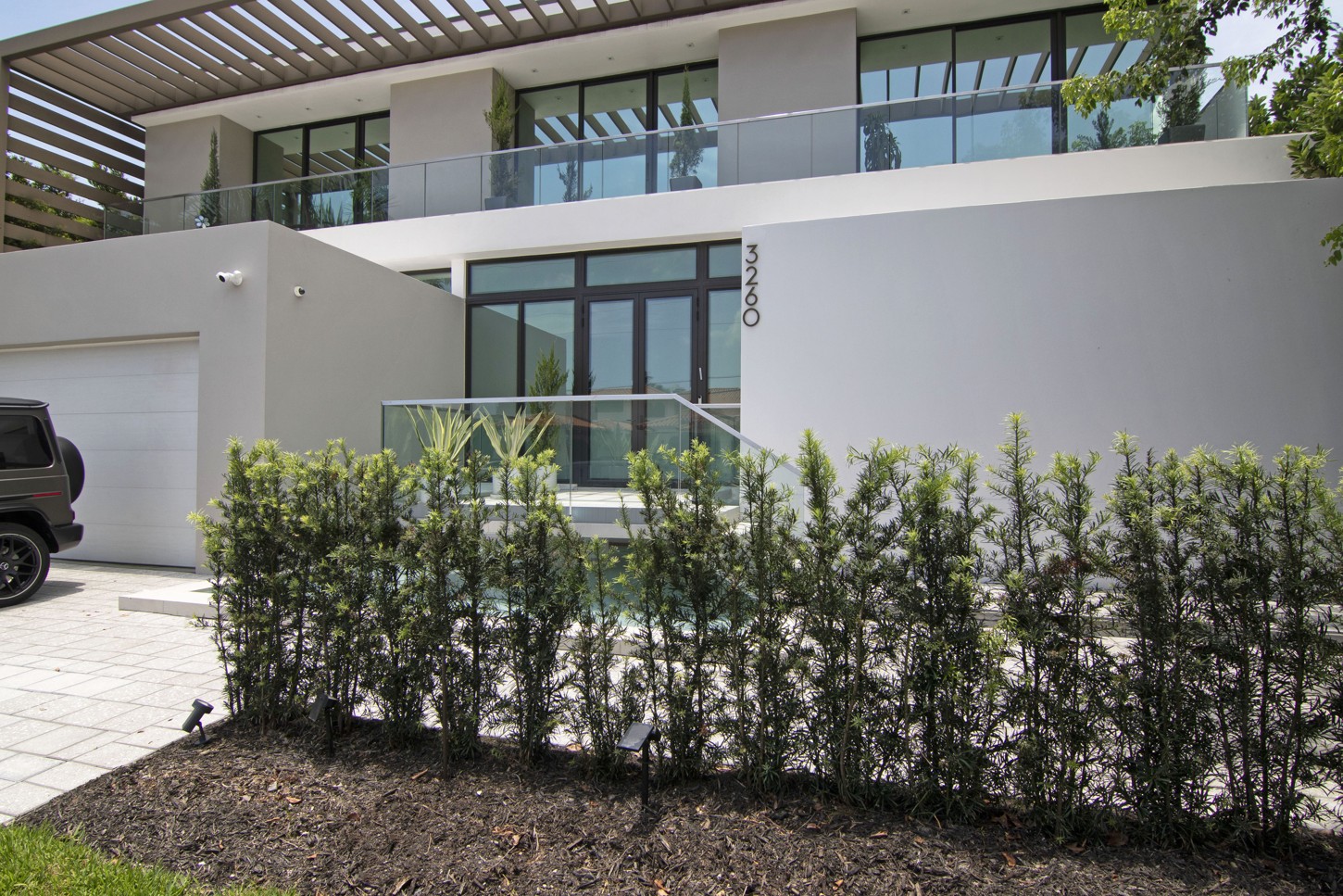 Front exterior of a modern home with entrance and hedge in Eastern Shores, North Miami