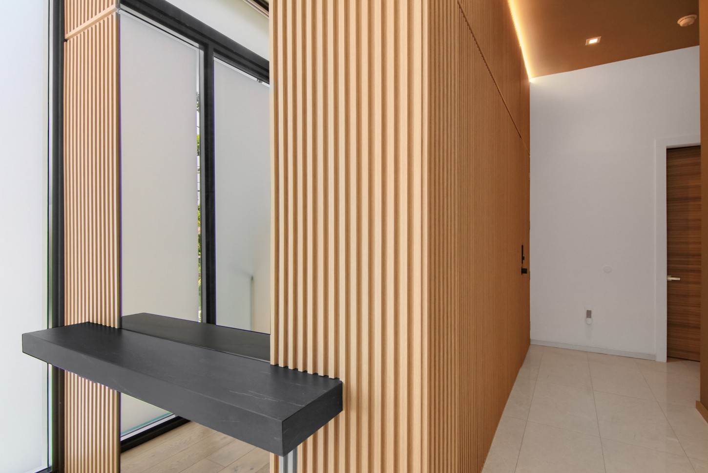 Hallway floating console shelf against a wood slat wall in North Miami