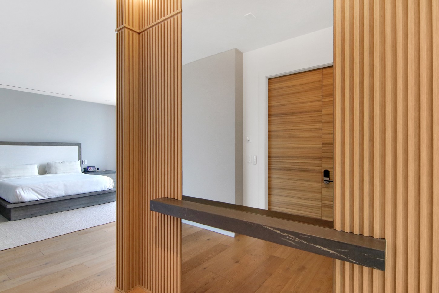 Custom wood slat column with a floating stone shelf in a North Miami master bedroom