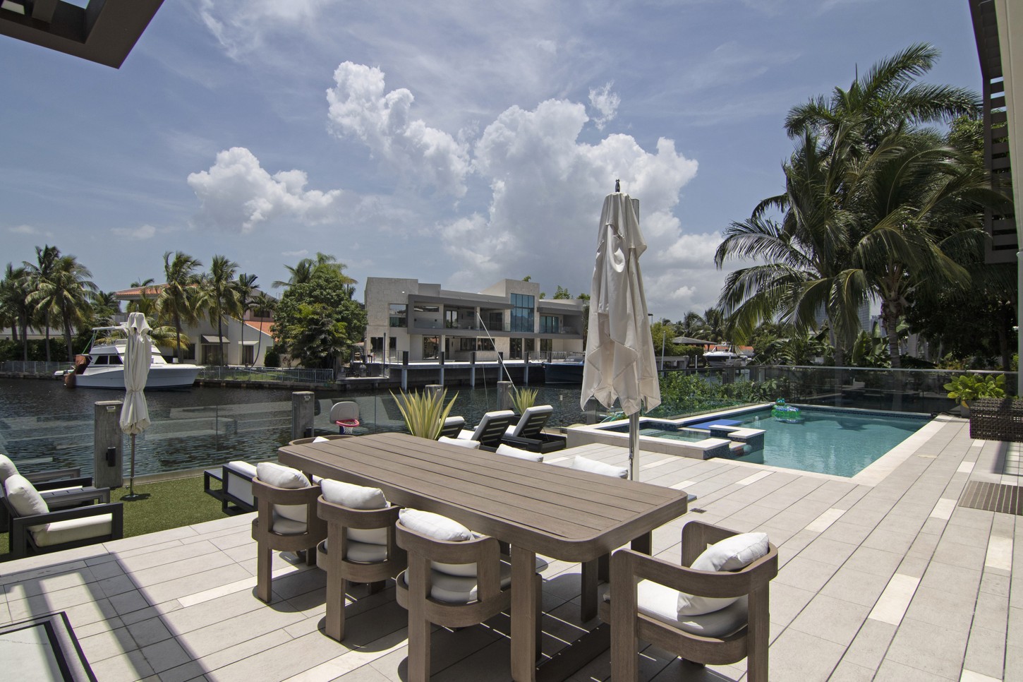 Custom outdoor dining table by the pool with a waterfront view in North Miami