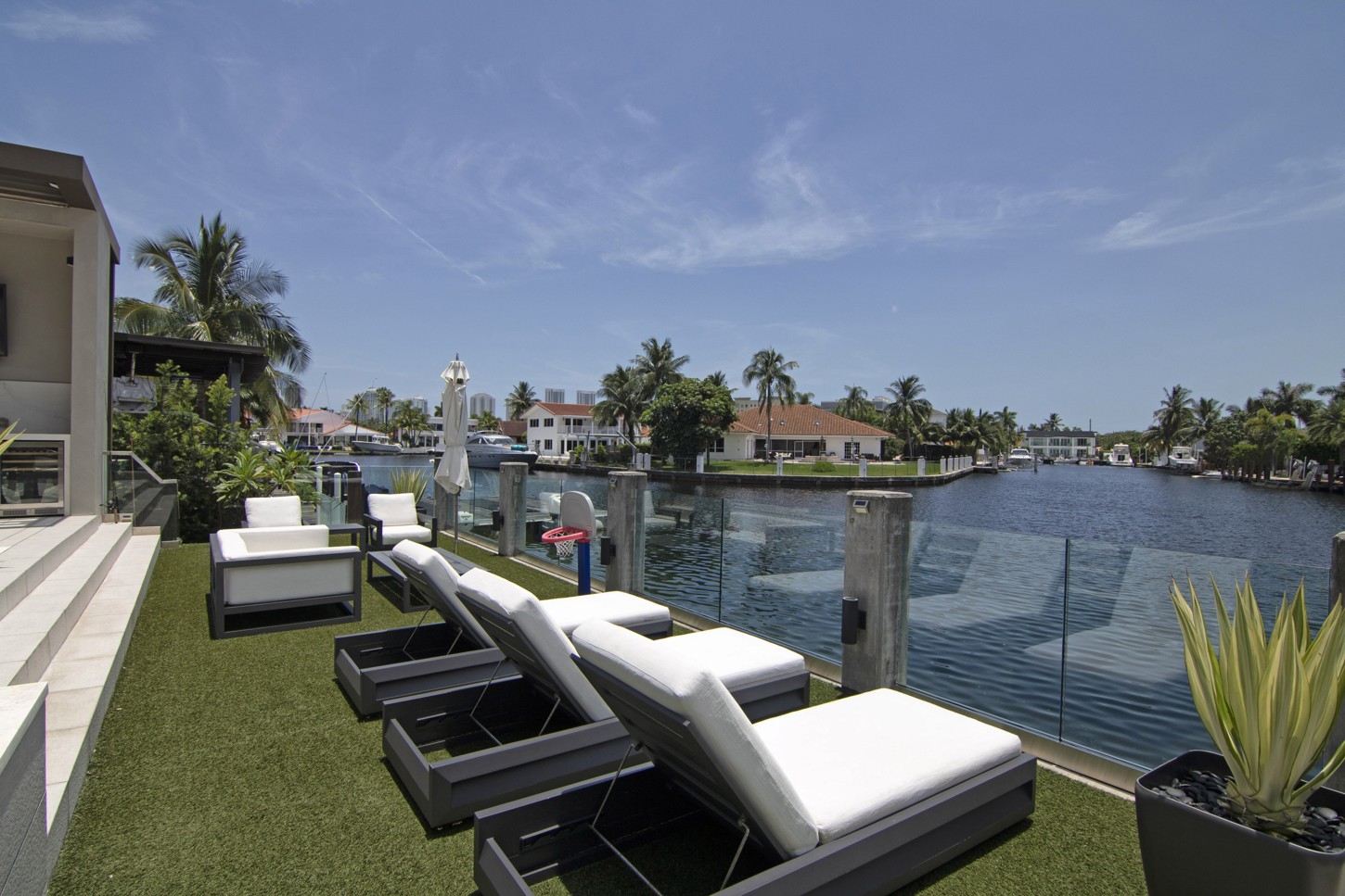 Custom outdoor lounge furniture on a turf deck with waterfront view in North Miami