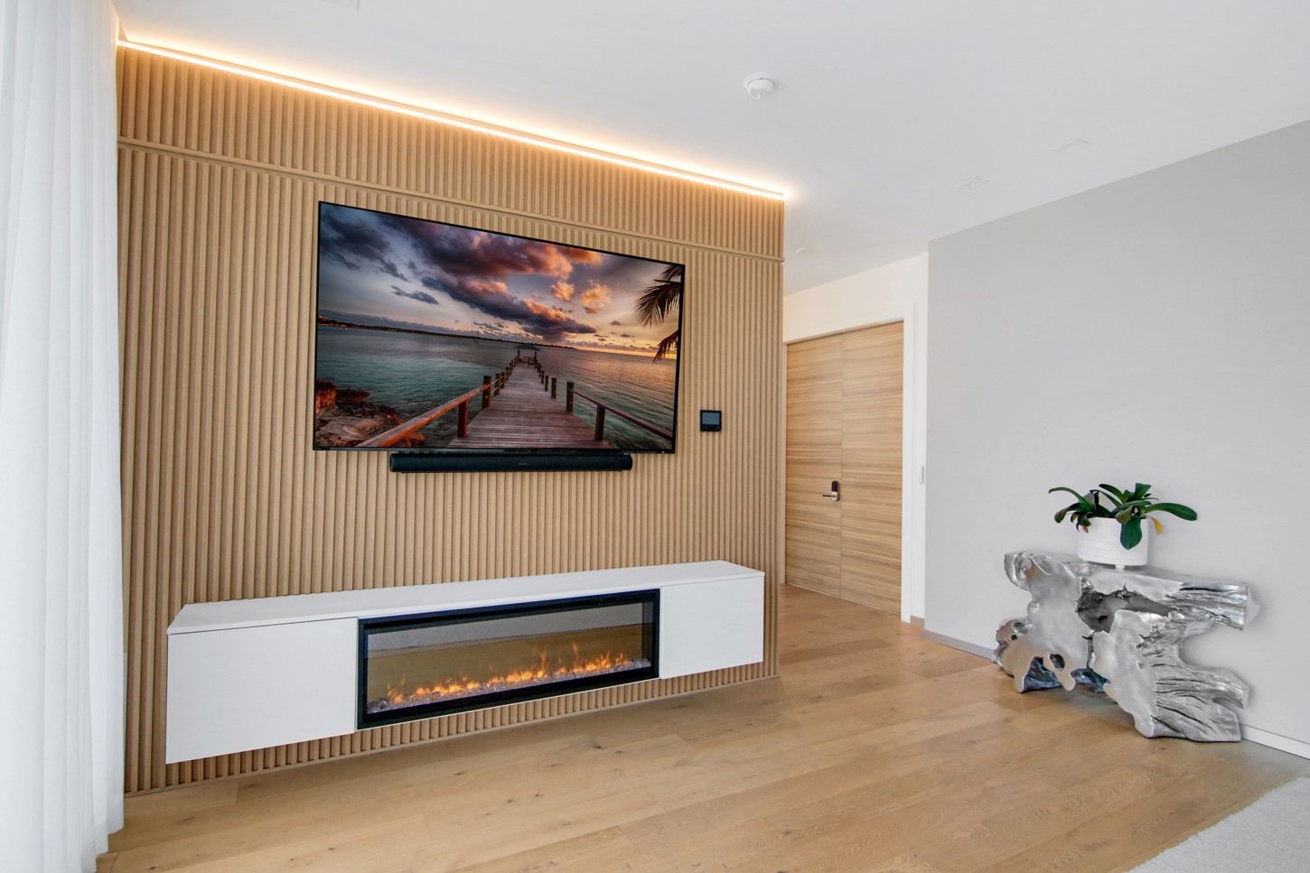 Wood slat TV wall with LED lighting, floating console and fireplace in North Miami