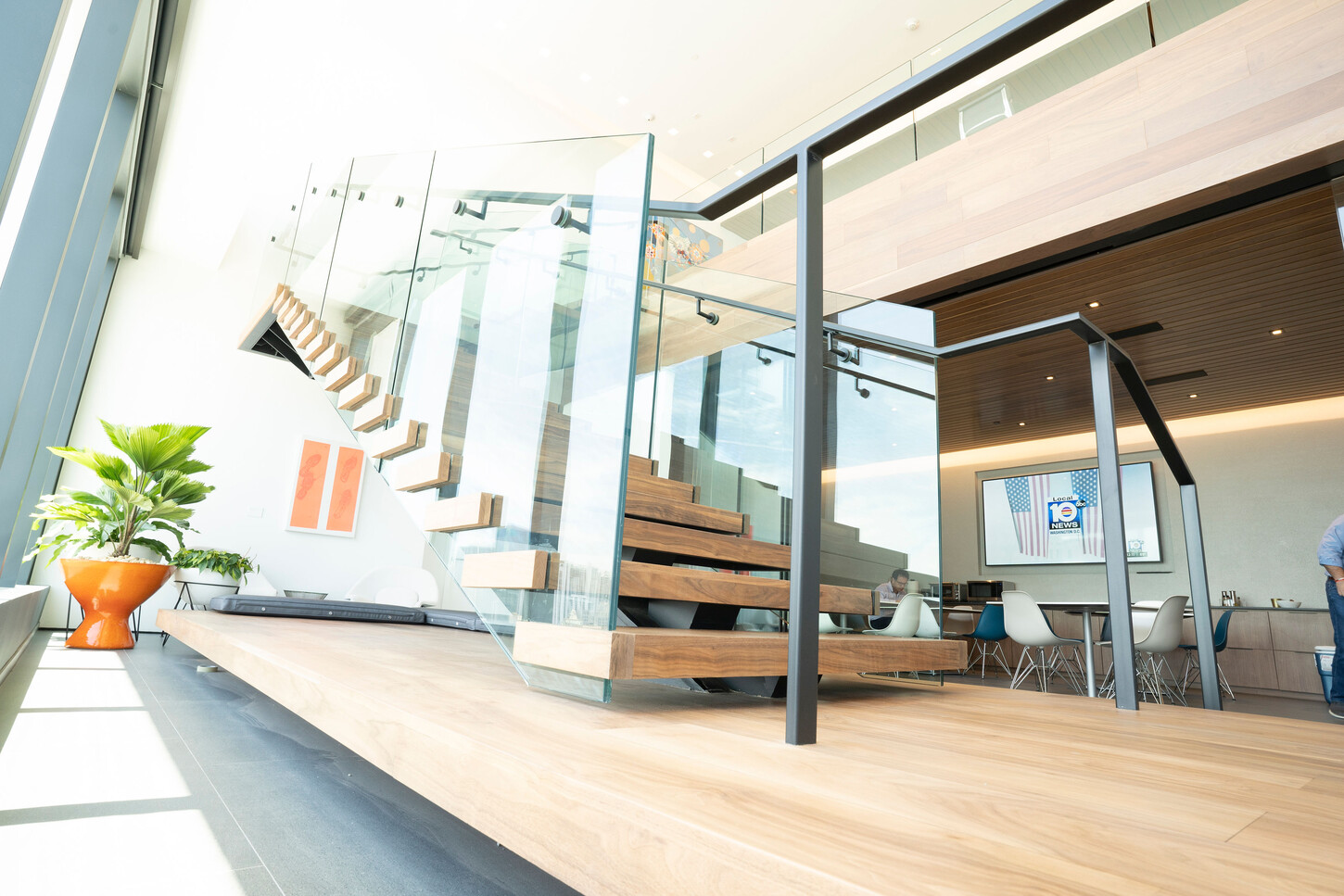 Floating staircase with glass balustrade and wood floor landing in a Miami high-rise lounge