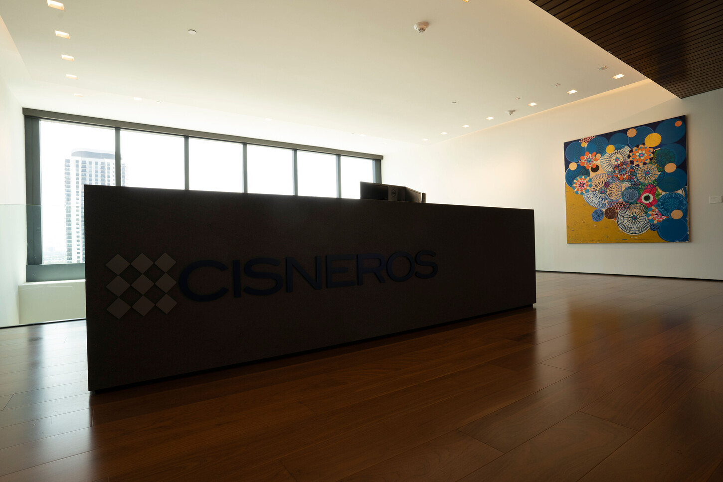 Custom reception desk with stone-toned front on a wood floor in a Miami office lobby