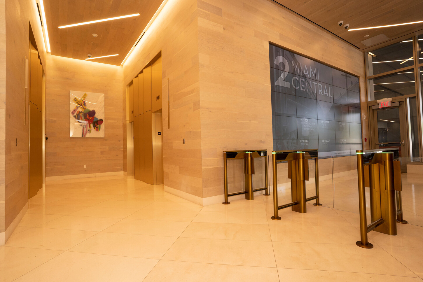 Wood-paneled elevator entrance and security turnstiles in a Miami high-rise lobby