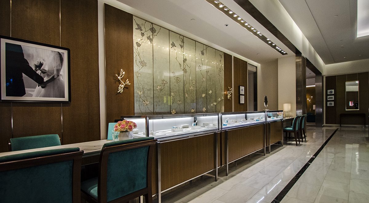 Custom wood wall panels, floral feature wall, jewelry display cases, and custom seating at the Tiffany Bal Harbour Shops boutique
