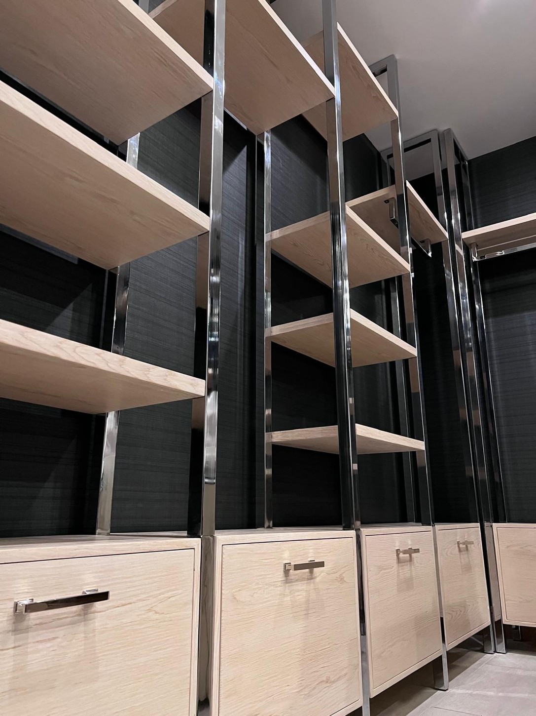 Custom wood veneer drawers with polished metal frame shelving detail