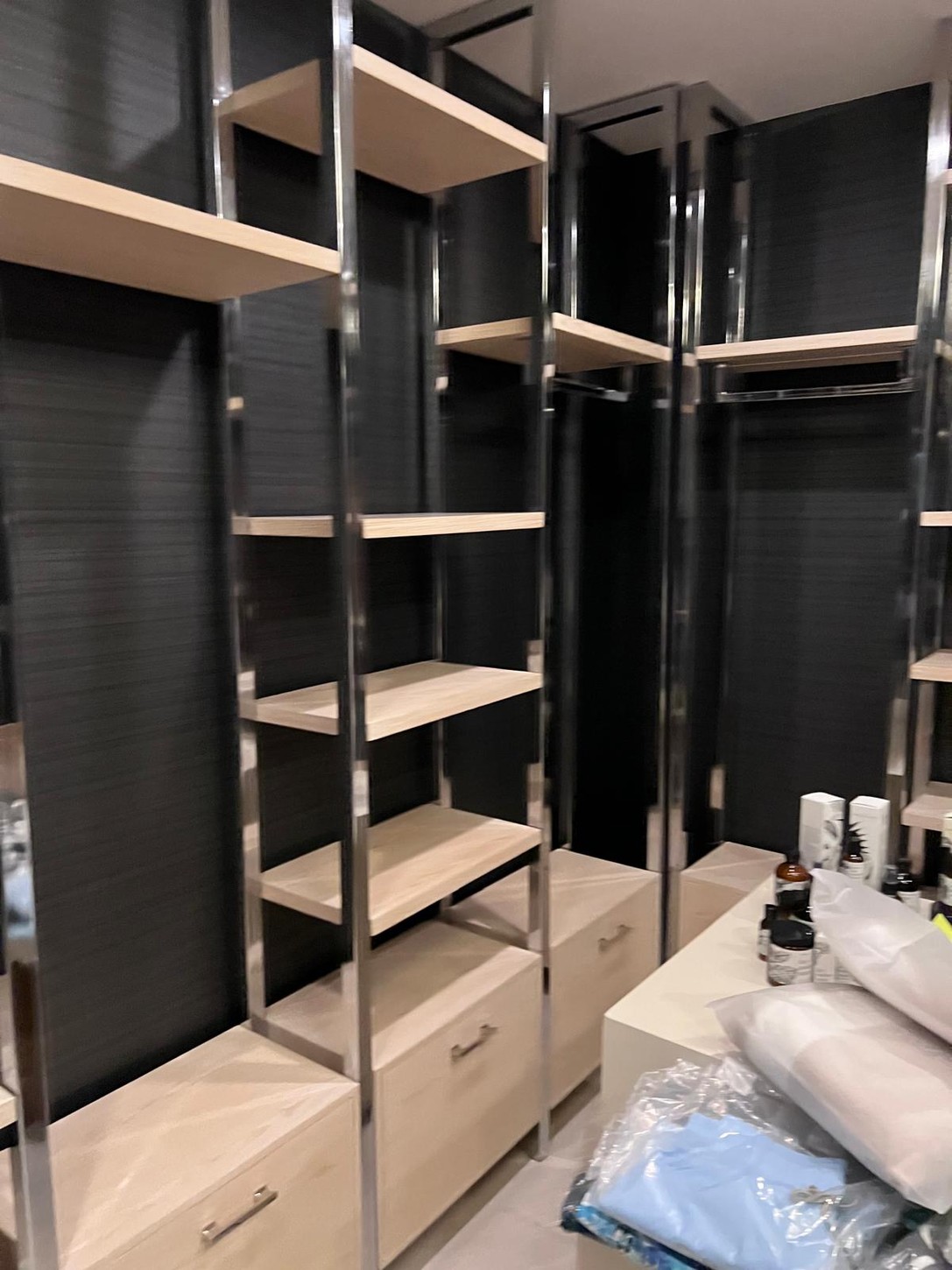 Wood veneer cabinetry drawers below polished metal frame shelving in the Chicago spa