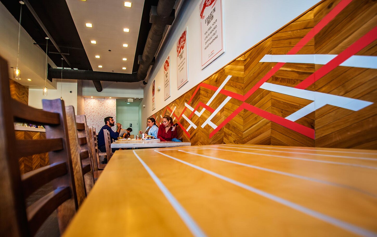 Restaurant wall in Wynwood with chevron wood and red and white accent lines above a custom wood table