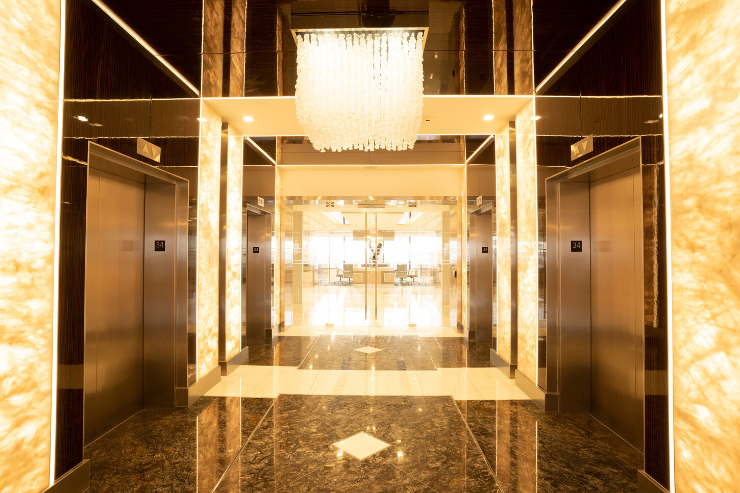 Elevator vestibule with a crystal chandelier and marble floor at the Zarco law firm in Florida